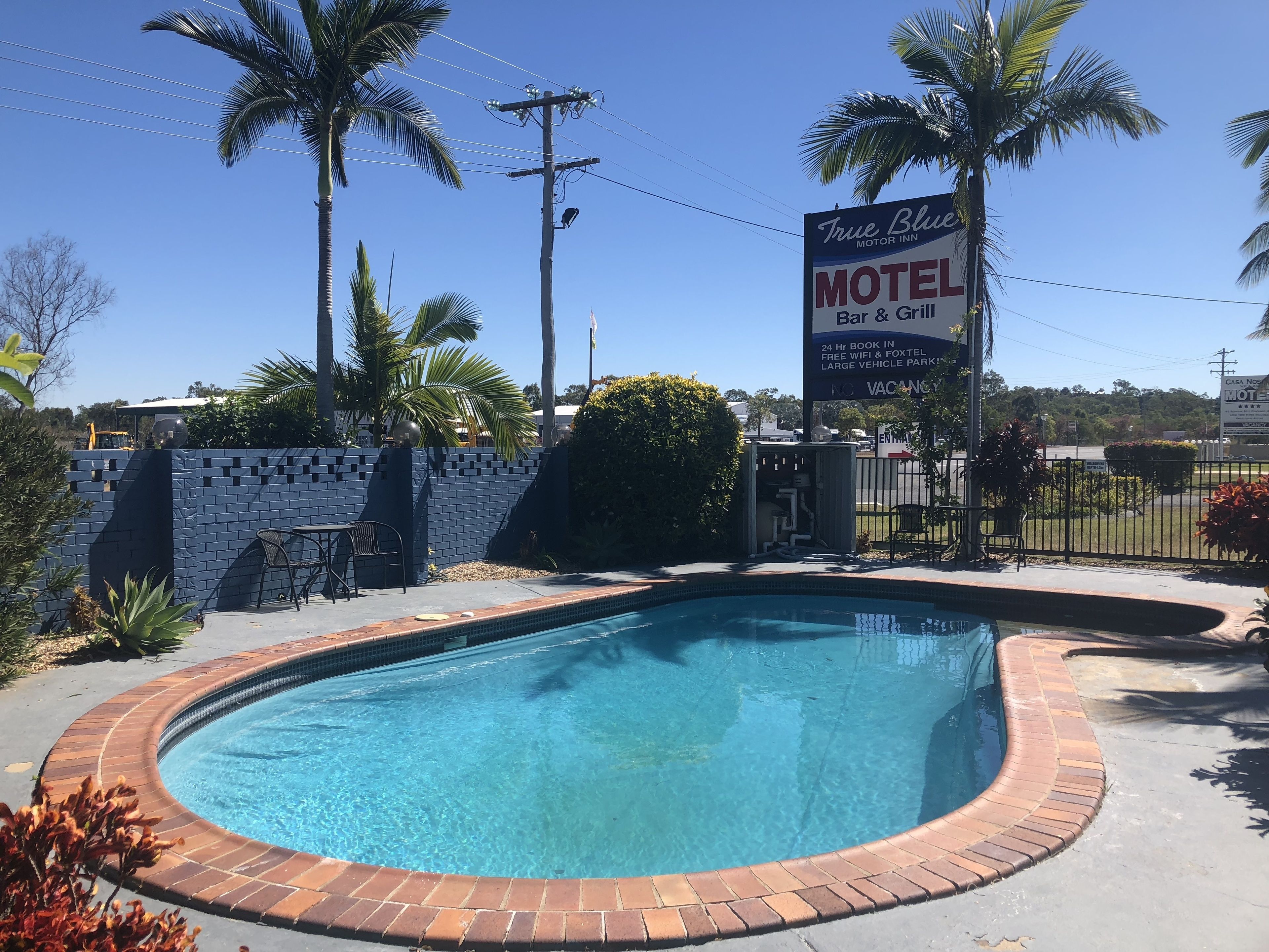 A motel with a pool, a bar & grill, and a sign advertising 24-hour booking and free WiFi.