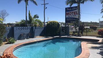 A motel with a pool, a bar & grill, and a sign advertising 24-hour booking and free WiFi.