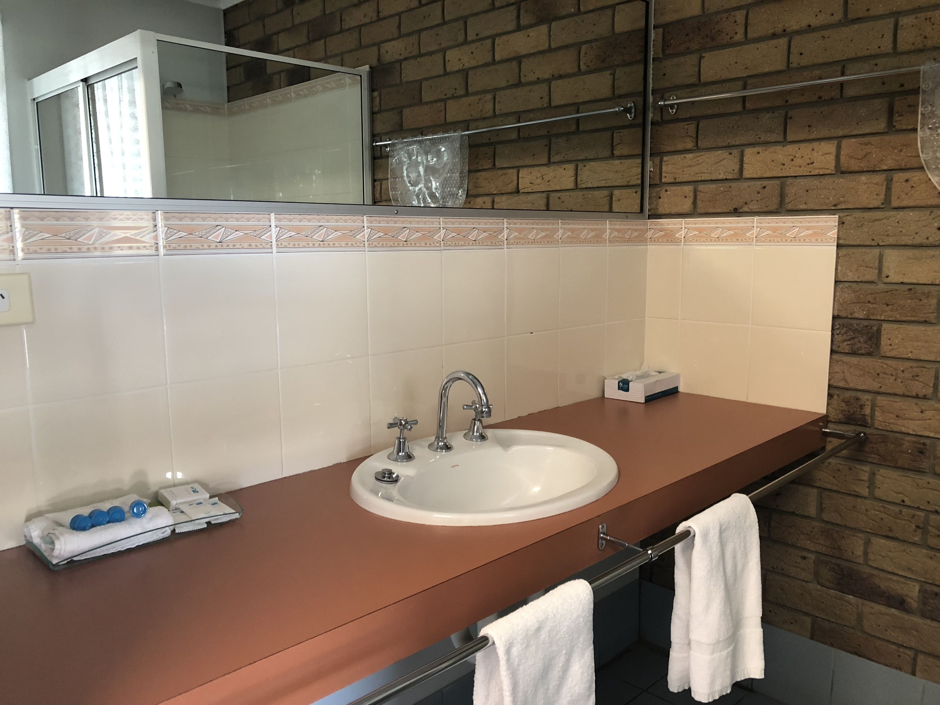 Un baño con lavamanos blanco, un espejo y un perchero para toallas.