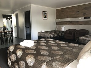 A hotel room with a bed, two armchairs, a small table, and a picture on the wall.