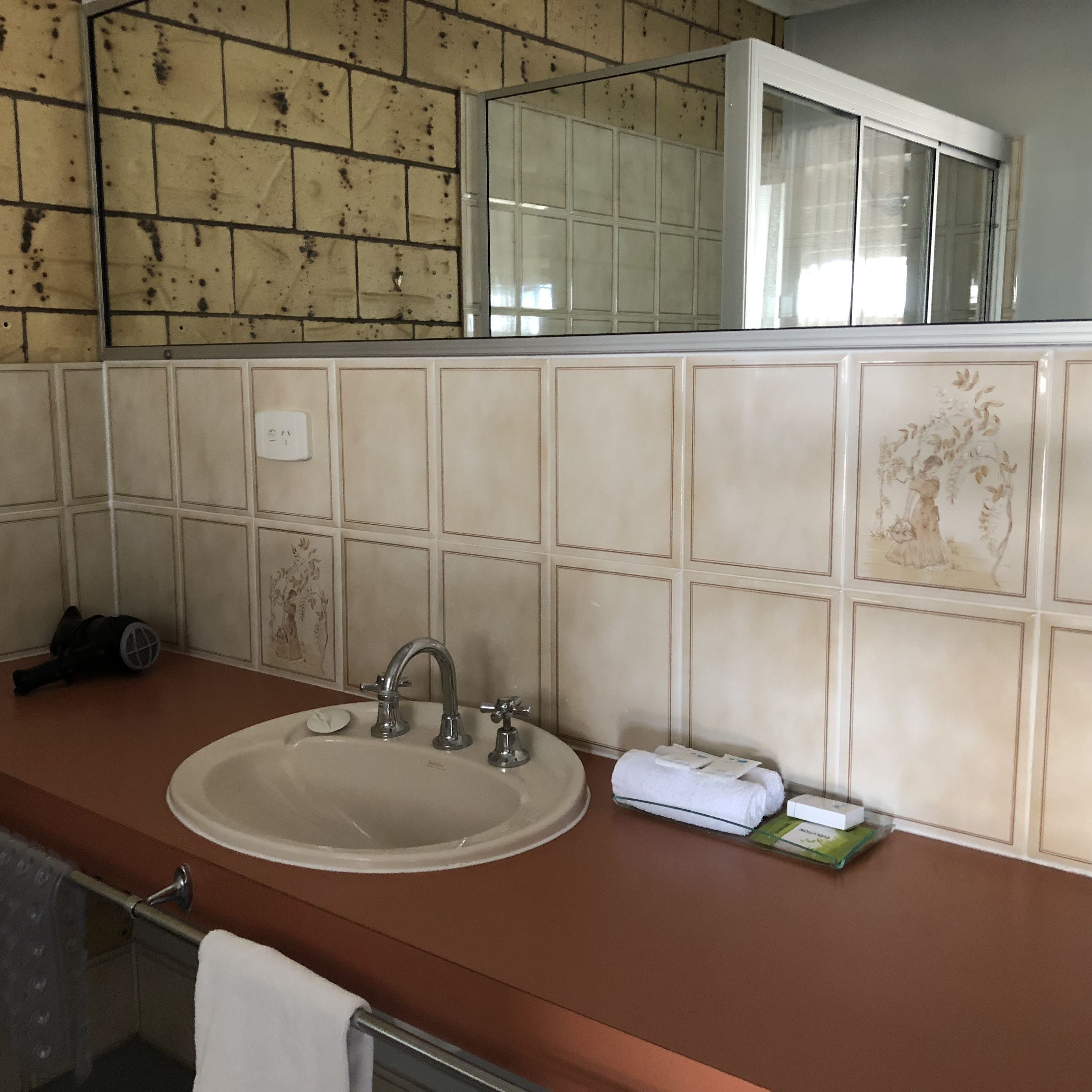 A bathroom with a sink, mirror, and tiled walls.