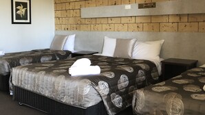 A hotel room with two beds, a brick-patterned headboard, and a framed picture on the wall. - True Blue Motor Inn (Parkhurst)