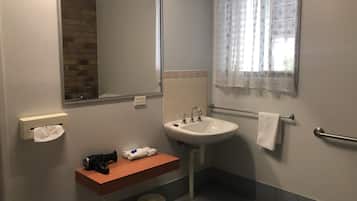 A bathroom with a sink, mirror, towel rack, and a window with patterned curtains.