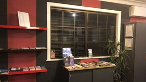 A room with a window, shelves with books, a small table with magazines, and a potted plant. - True Blue Motor Inn (Parkhurst)