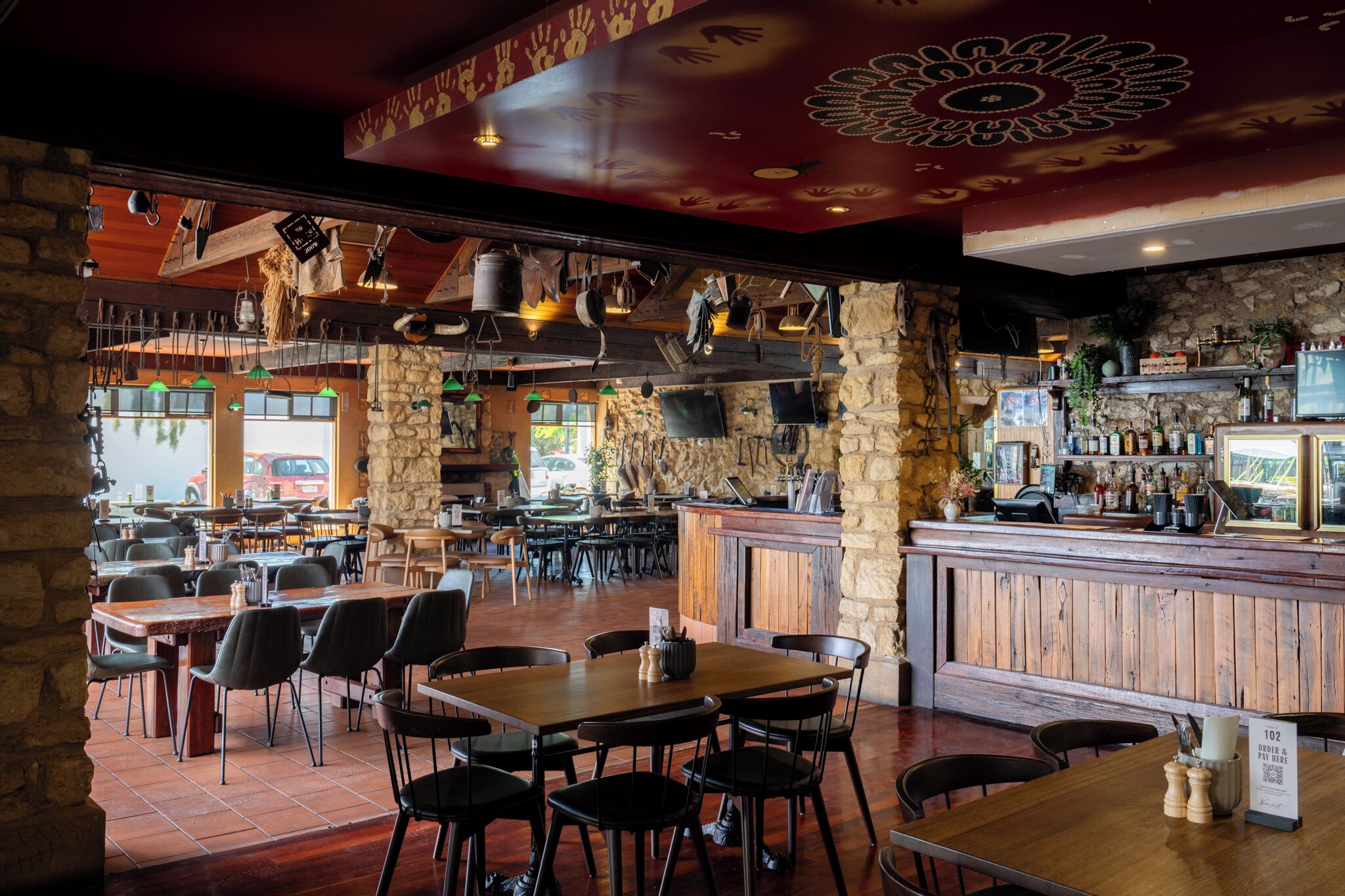 A restaurant with stone walls, wooden tables, and a bar area.