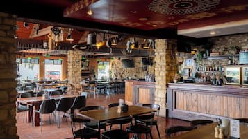 A restaurant with stone walls, wooden tables, and a bar area.