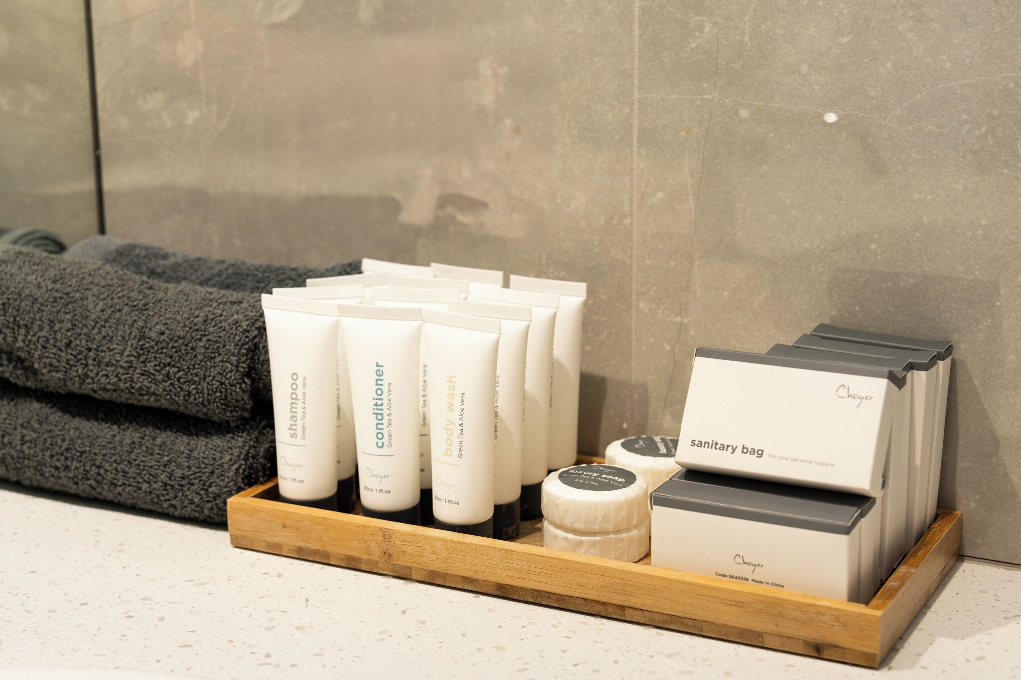 A wooden tray with various toiletries including shampoo, conditioner, body wash, and a sanitary bag.