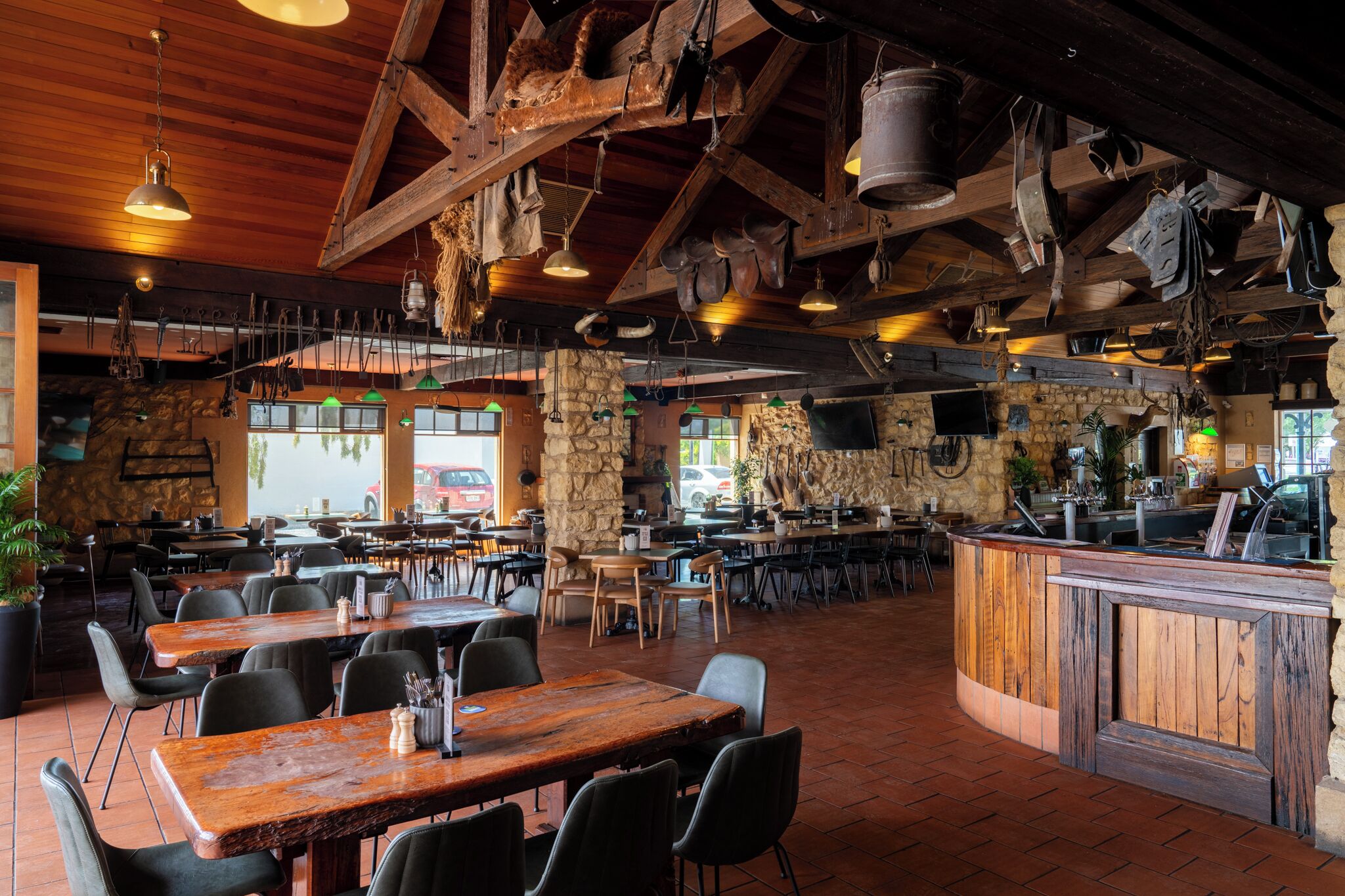 L’intérieur de ce restaurant rustique est agrémenté de tables en bois, de murs en pierre et d’ustensiles de cuisine suspendus.