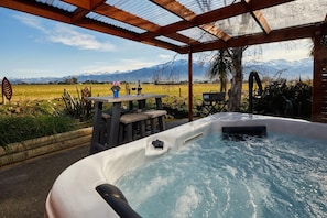 A hot tub with a view of mountains, a table with wine glasses, and a pergola structure. - Brook House Bed & Breakfast and Cottages (Kaikōura)