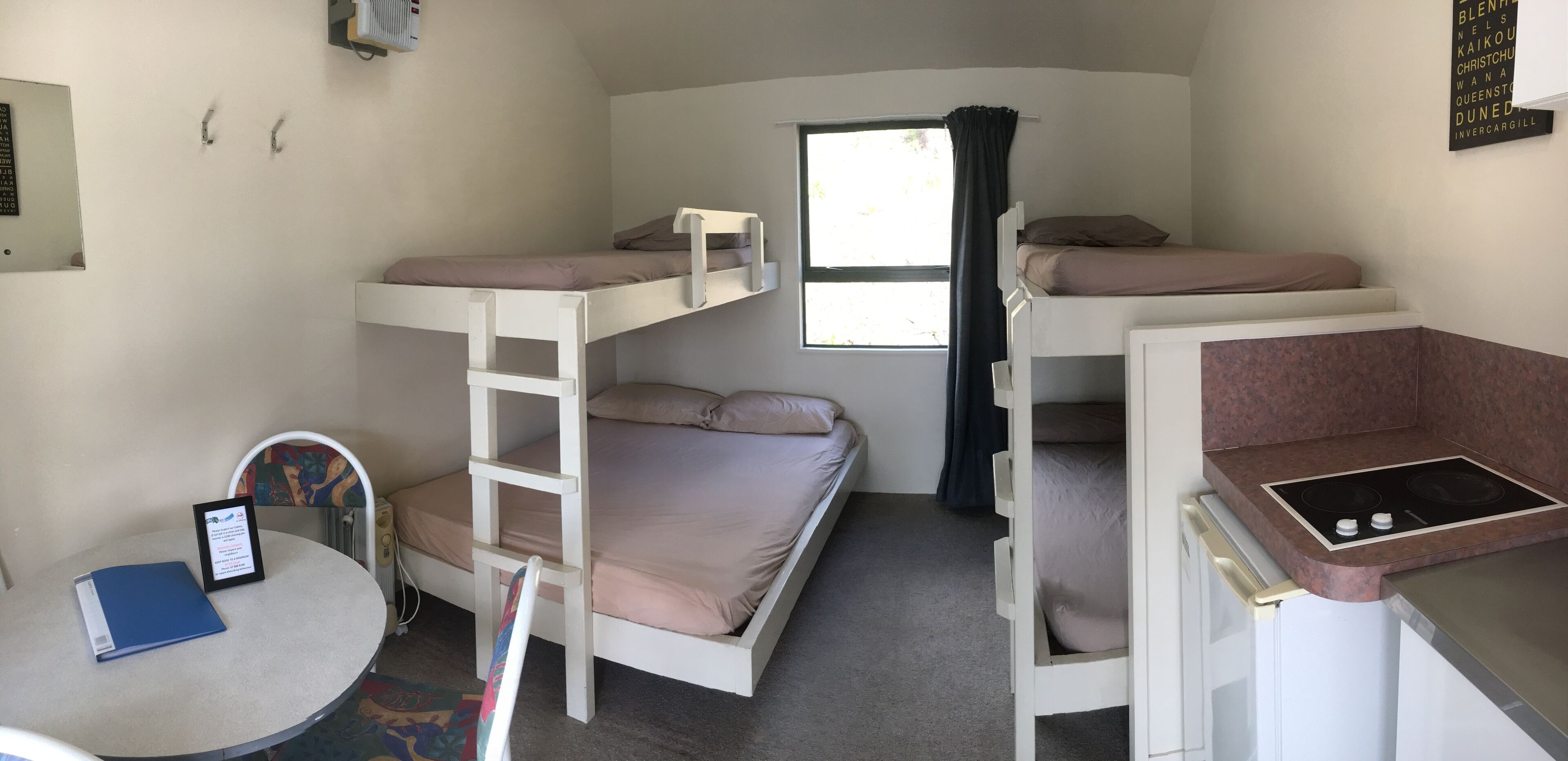 Une chambre avec un lit superposé, une petite table et une fenêtre.