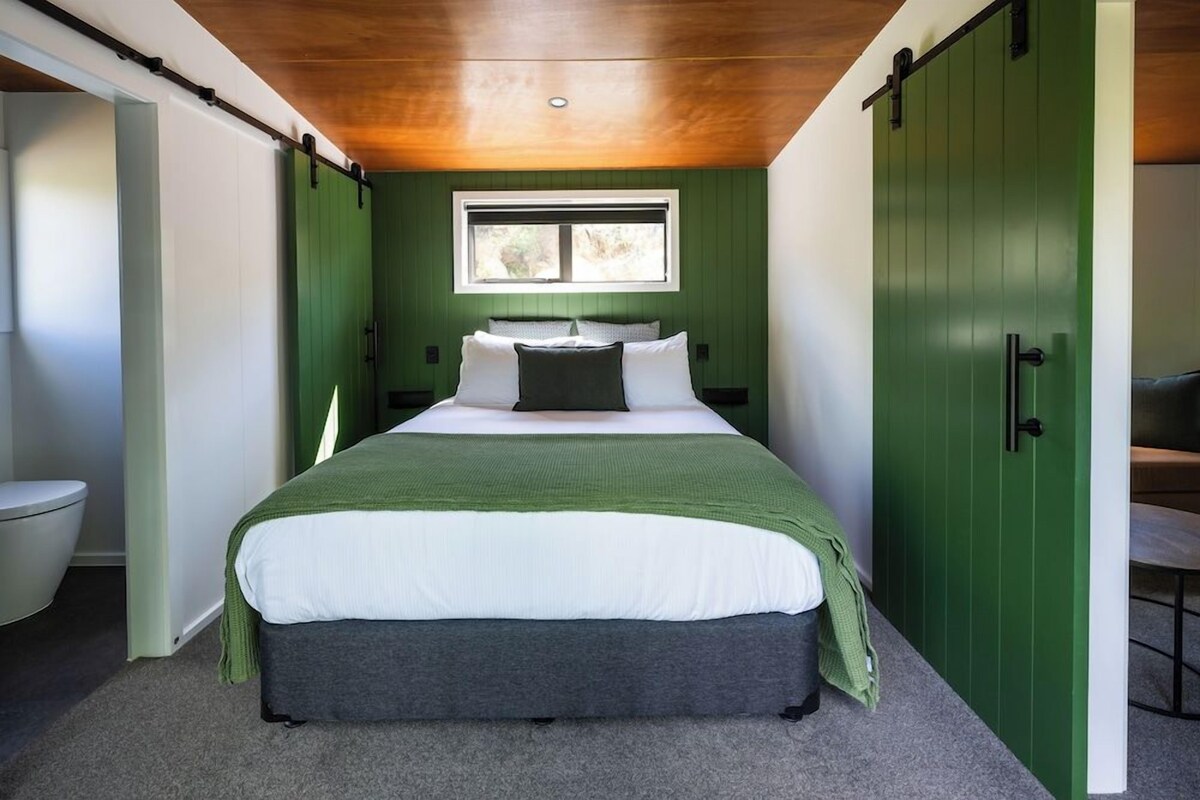 Un dormitorio con cama, ventana y paredes verdes.