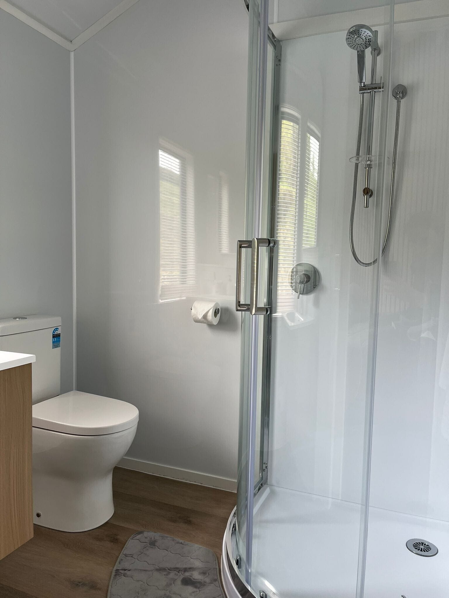 A modern bathroom with a glass-enclosed shower, a toilet, and a bidet.