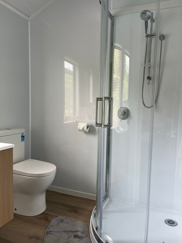A modern bathroom with a glass-enclosed shower, a toilet, and a bidet. - Opal Hot Springs & Holiday Park (Okauia)