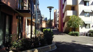 A multi-story residential building with balconies, a paved driveway, and bicycles parked outside. - Sydney University Village (Newtown)