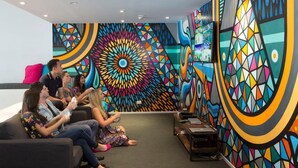 A vibrant, geometrically patterned wall in a modern lounge area with a sofa and a coffee table. - Sydney University Village (Newtown)