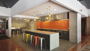 A modern kitchen with a central island, bar stools, and pendant lighting. - Sydney University Village (Newtown)