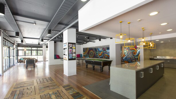 A spacious lobby with a pool table, artwork on the walls, and a modern bar area. - Sydney University Village (Newtown)