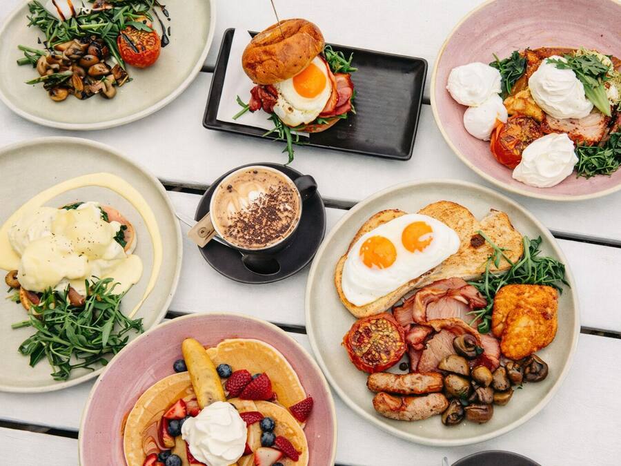 Una selezione di piatti per la colazione, tra cui uova, pancetta, funghi e frutti di bosco.