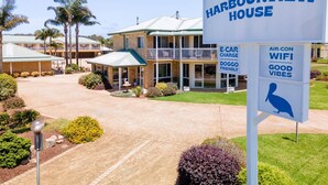 A Harbourview House with a sign indicating amenities like e-car charging, dog-friendly policy, and air-con with wifi. - Harbourview House (Bermagui)
