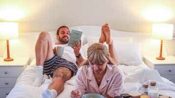 Un dormitorio con cama, lámparas de noche, mesita de noche y una bandeja con alimentos para el desayuno.
