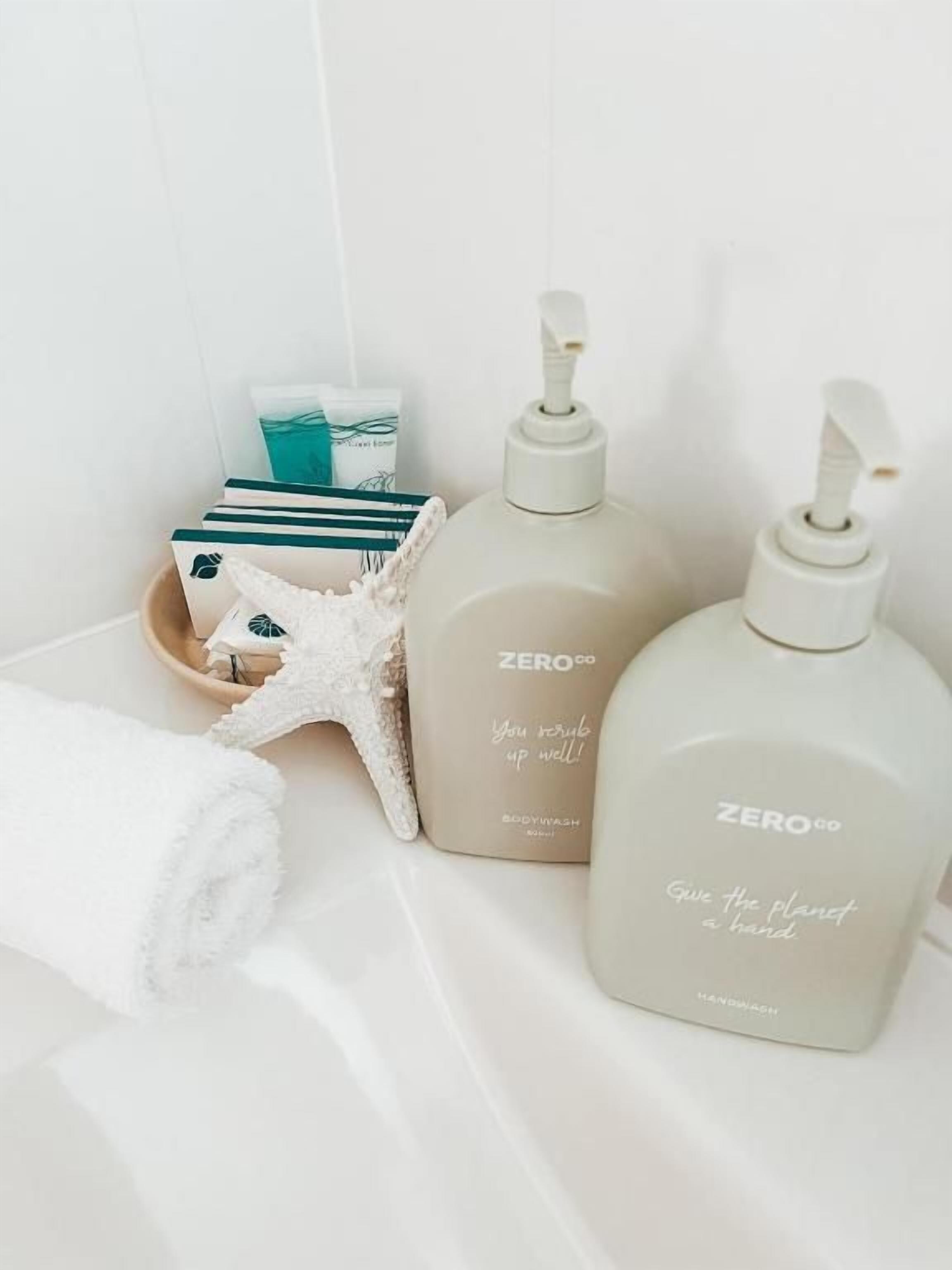 A bathroom with a white towel, a starfish decoration, and two bottles of ZERO.co body wash.