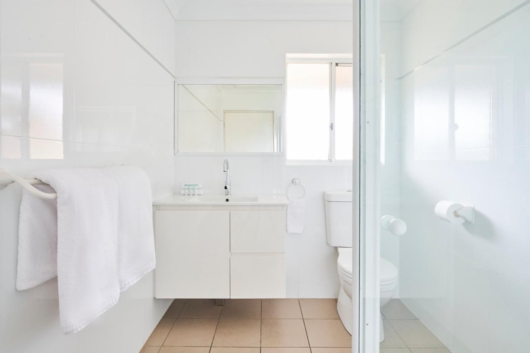 A modern bathroom with a glass shower enclosure, a white sink, and a toilet.