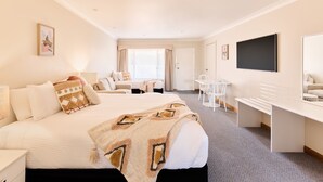 A hotel room with a large bed, a desk, a chair, a TV, and a window with curtains. - Harbourview House (Bermagui)
