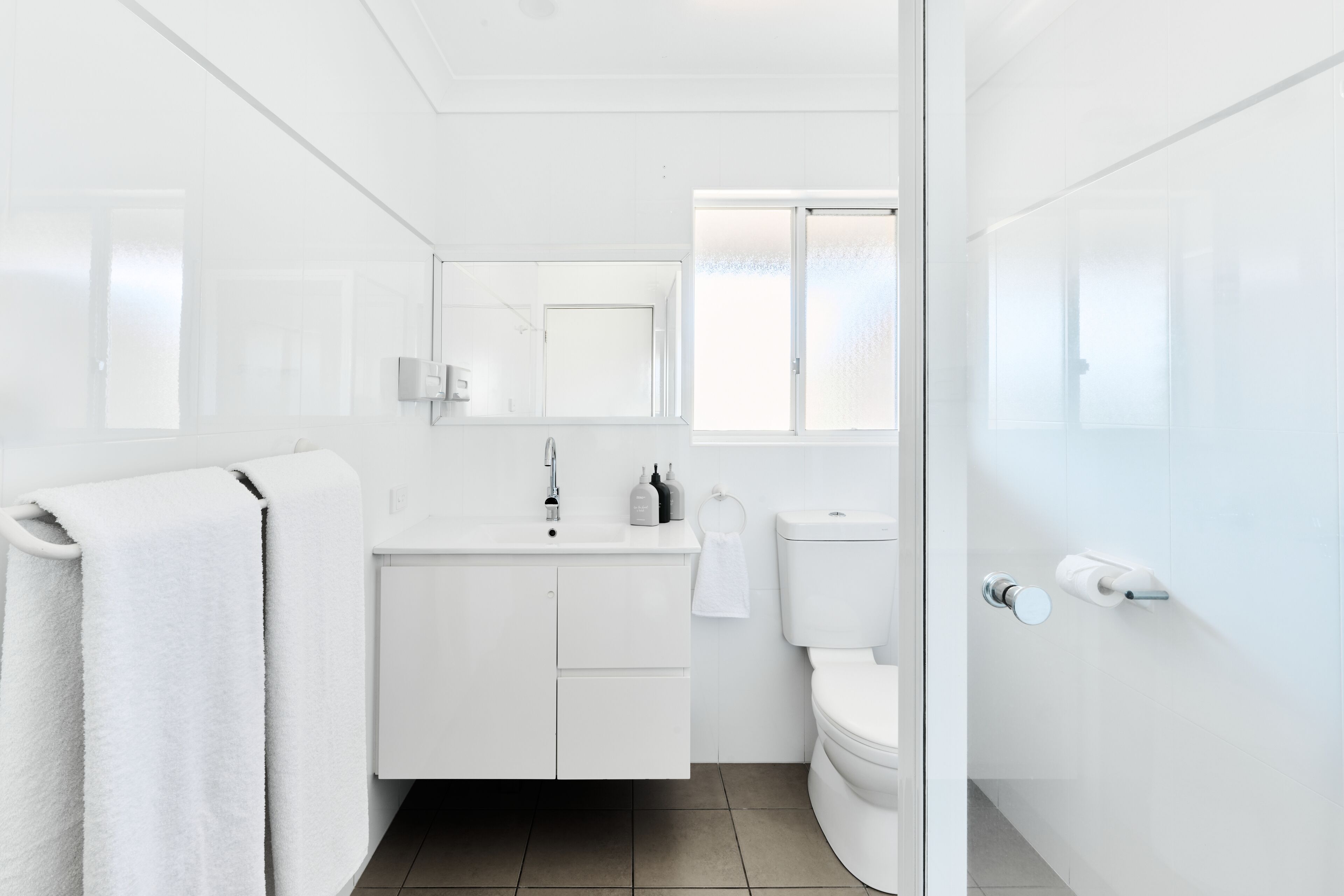 Une salle de bain moderne avec un meuble-lavabo blanc, des toilettes et un porte-serviettes.