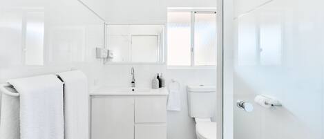 A modern bathroom with a white vanity, a toilet, and a towel rack.