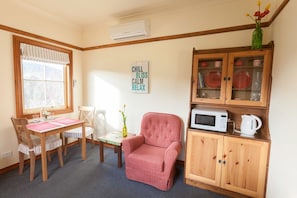 A cozy room with a dining table, chairs, a pink armchair, a cabinet with dishes, and a sign that says "CHILL BLISS CALM RELAX". - Margate Cottage Boutique Bed & Breakfast (Margate)