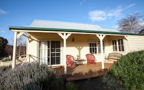 A house with a porch, red chairs, and a bench. - Margate Cottage Boutique Bed & Breakfast (Margate)