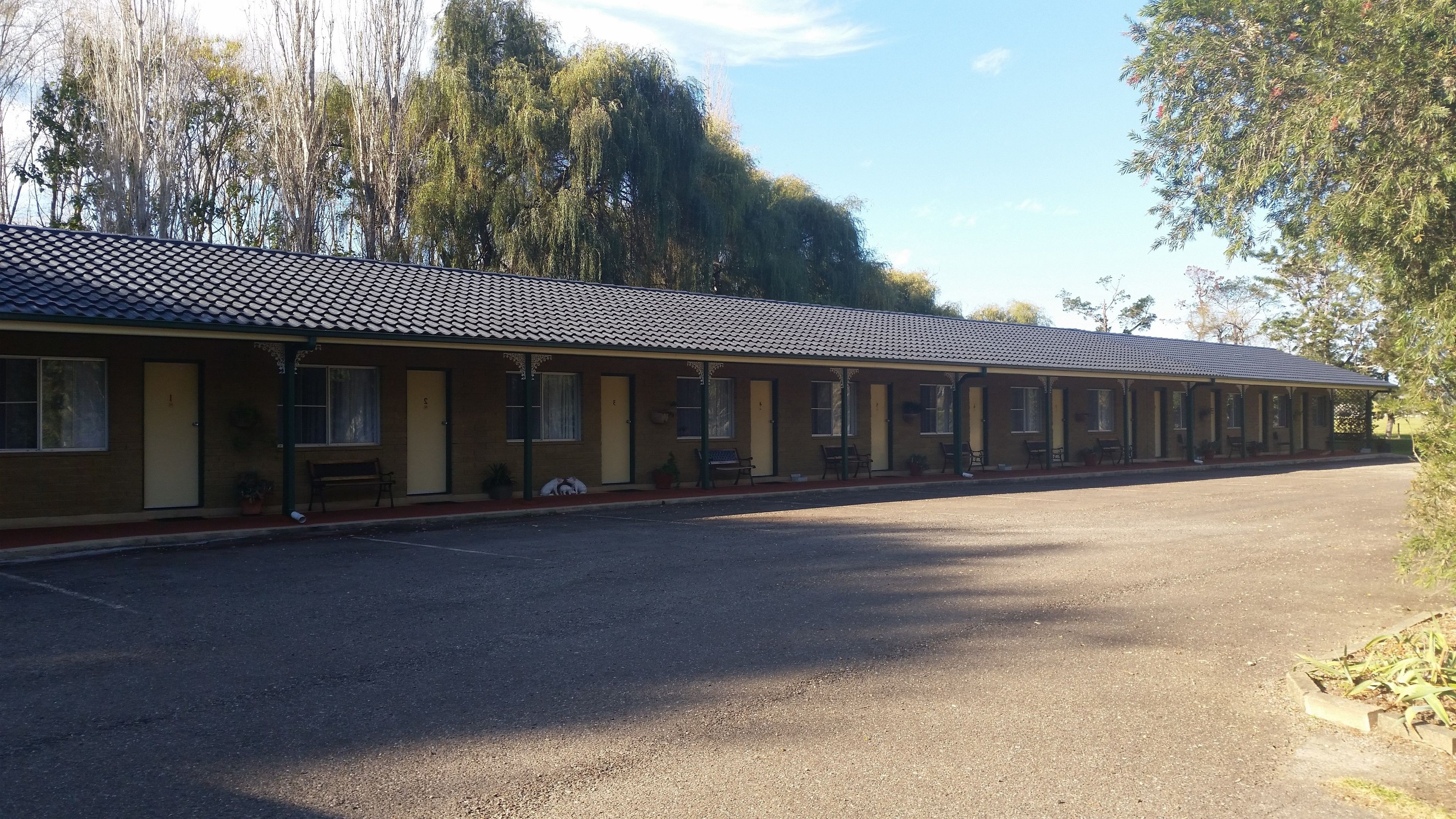 A row of motel rooms with a tiled roof, a covered walkway, and a parking lot.