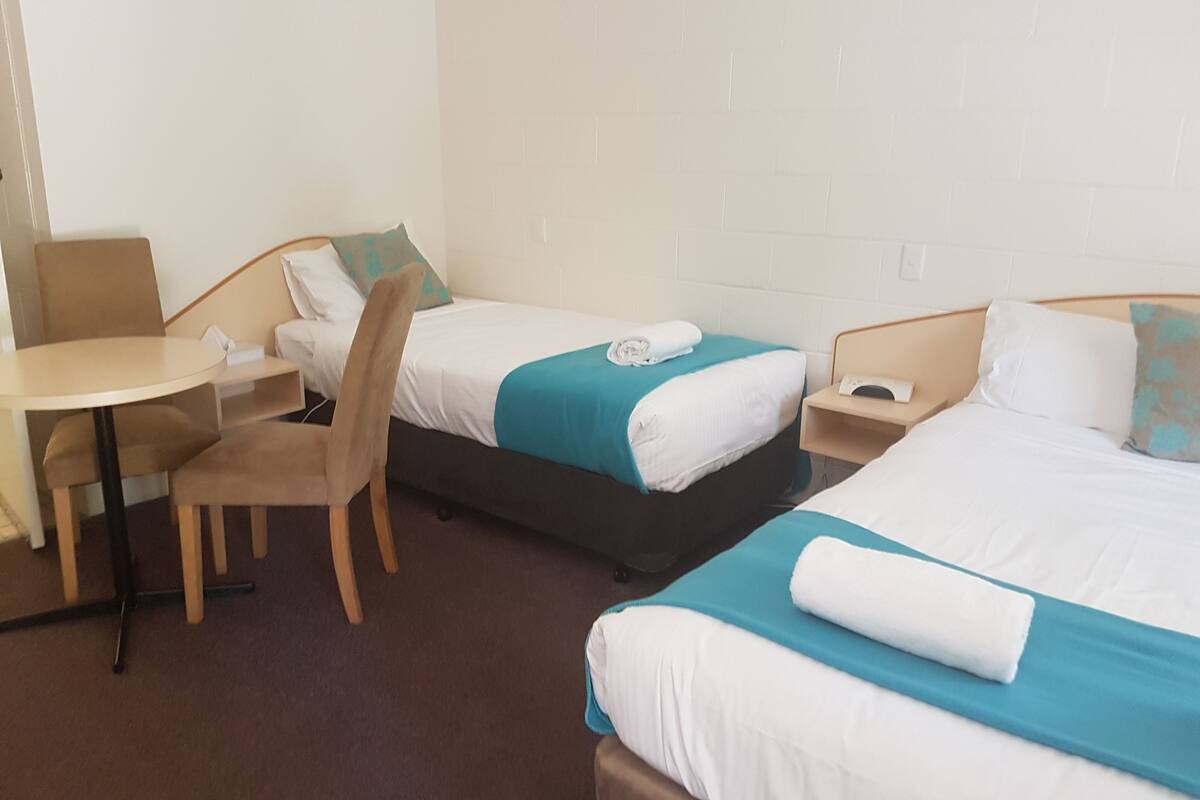 Ein Hotelzimmer mit zwei Betten, einem kleinen Tisch und einem Stuhl.