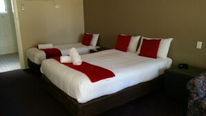A hotel room with two beds, each with white linens and red accents. There is a small table and a chair in the room. - Moruya Motel (Moruya)