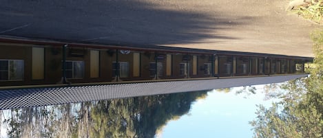 Un long motel d’un seul étage, avec une rangée de chambres dotées de grandes fenêtres et d’un toit recouvert de tuiles.