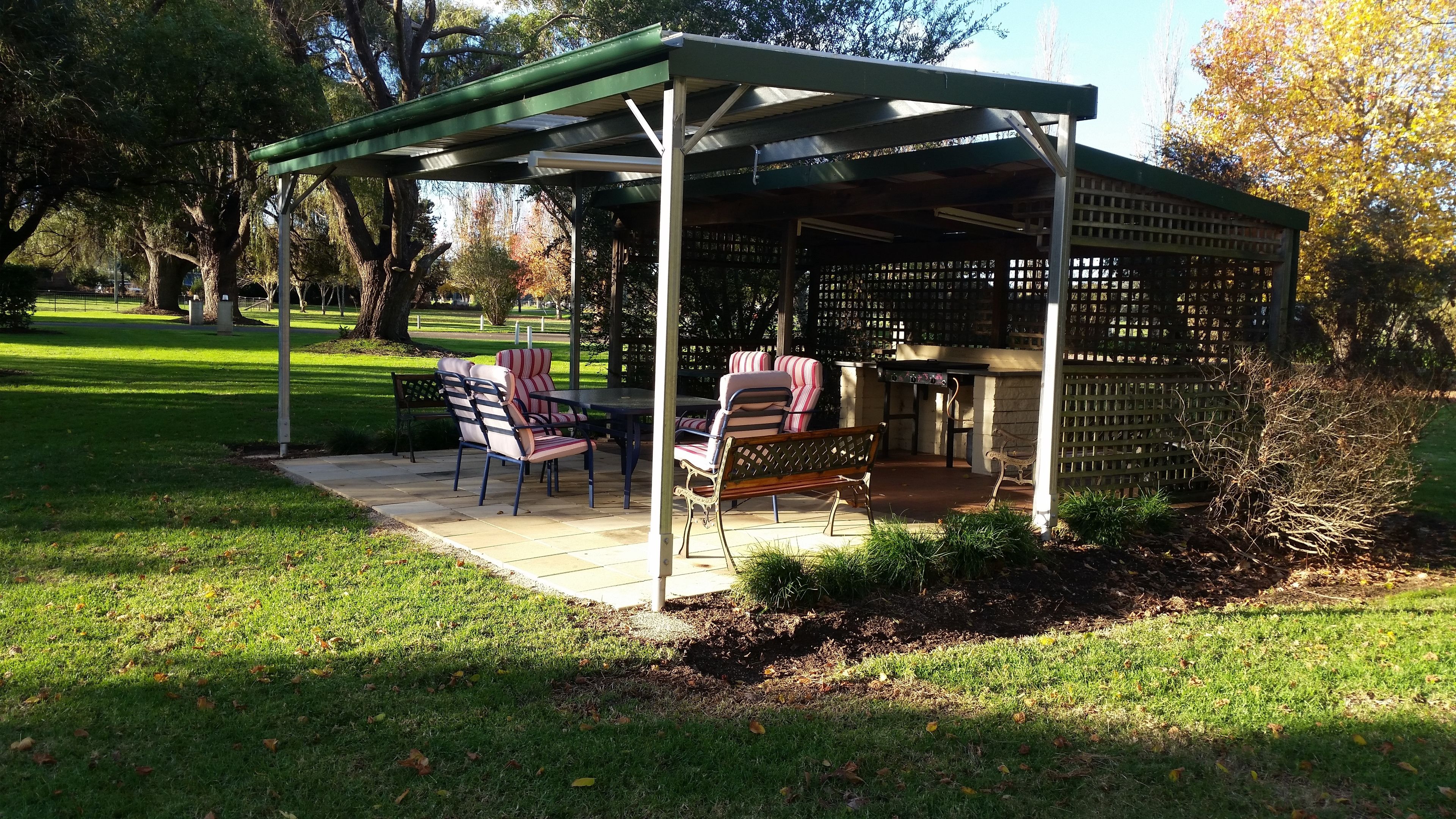 A covered outdoor seating area with a pergola, a table, and chairs.