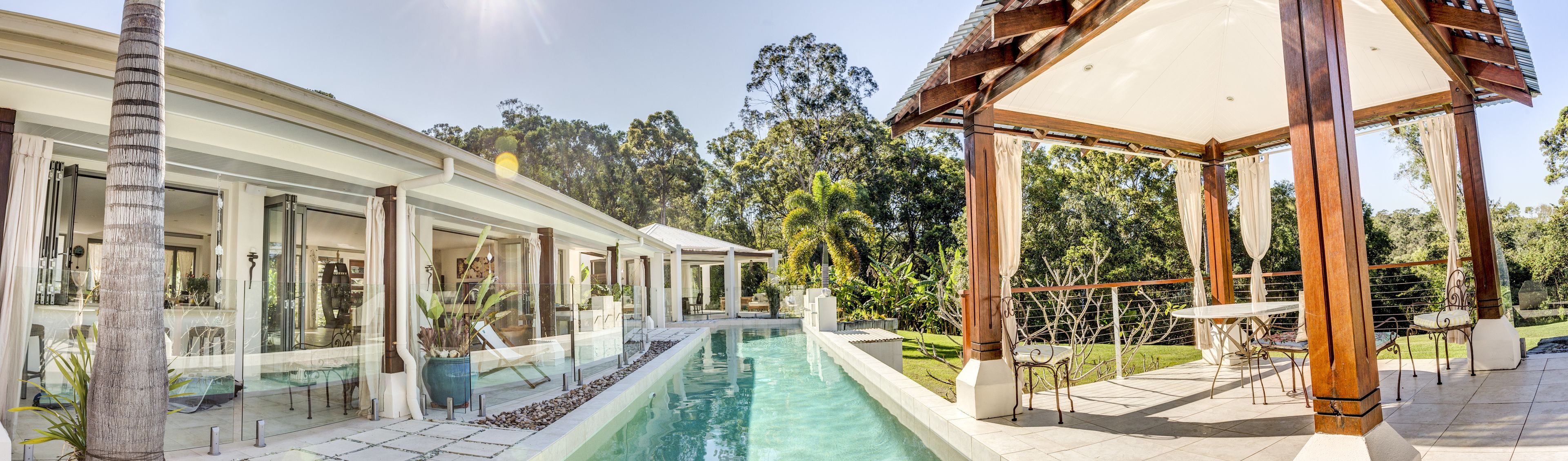 A pool area with a pergola, outdoor seating, and a covered patio.