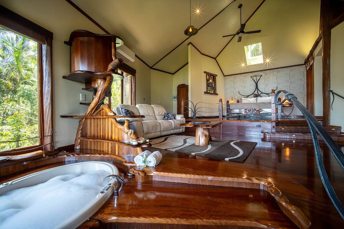 A spacious living area with a large wooden bathtub, a sofa, and a dining table.