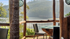 A wooden deck with a glass table and chairs overlooking a body of water and forested hills. - Secrets on the Lake (North Maleny)