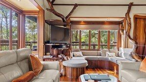 A spacious living area with a large L-shaped sectional sofa, a round coffee table, and a built-in fireplace. - Secrets on the Lake (North Maleny)