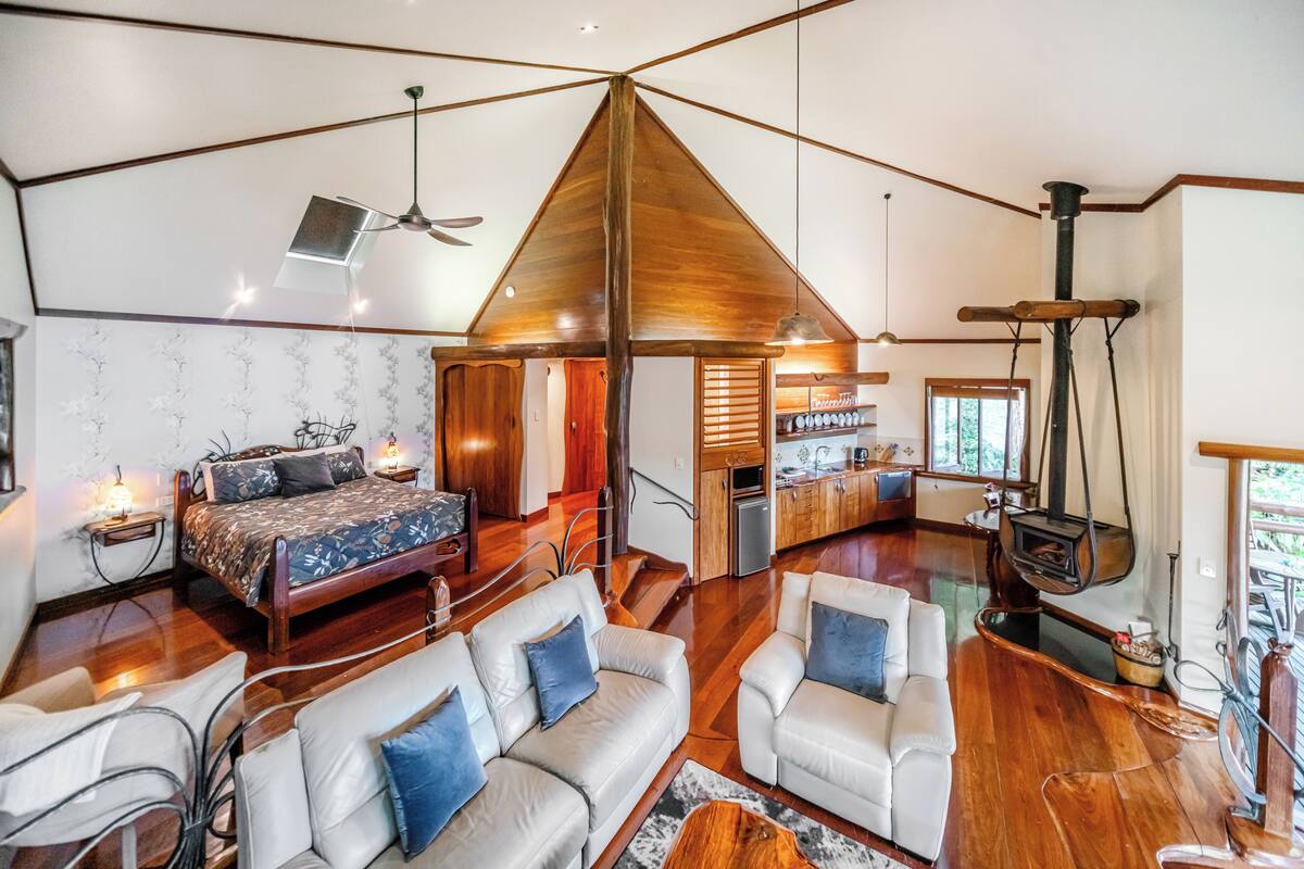 A spacious living area with a large bed, two sofas, a fireplace, and a kitchen area.