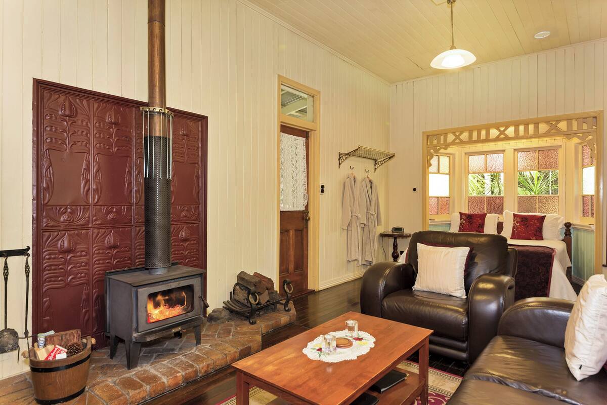 A cozy living room with a wood-burning stove, leather sofa, and a wooden coffee table.
