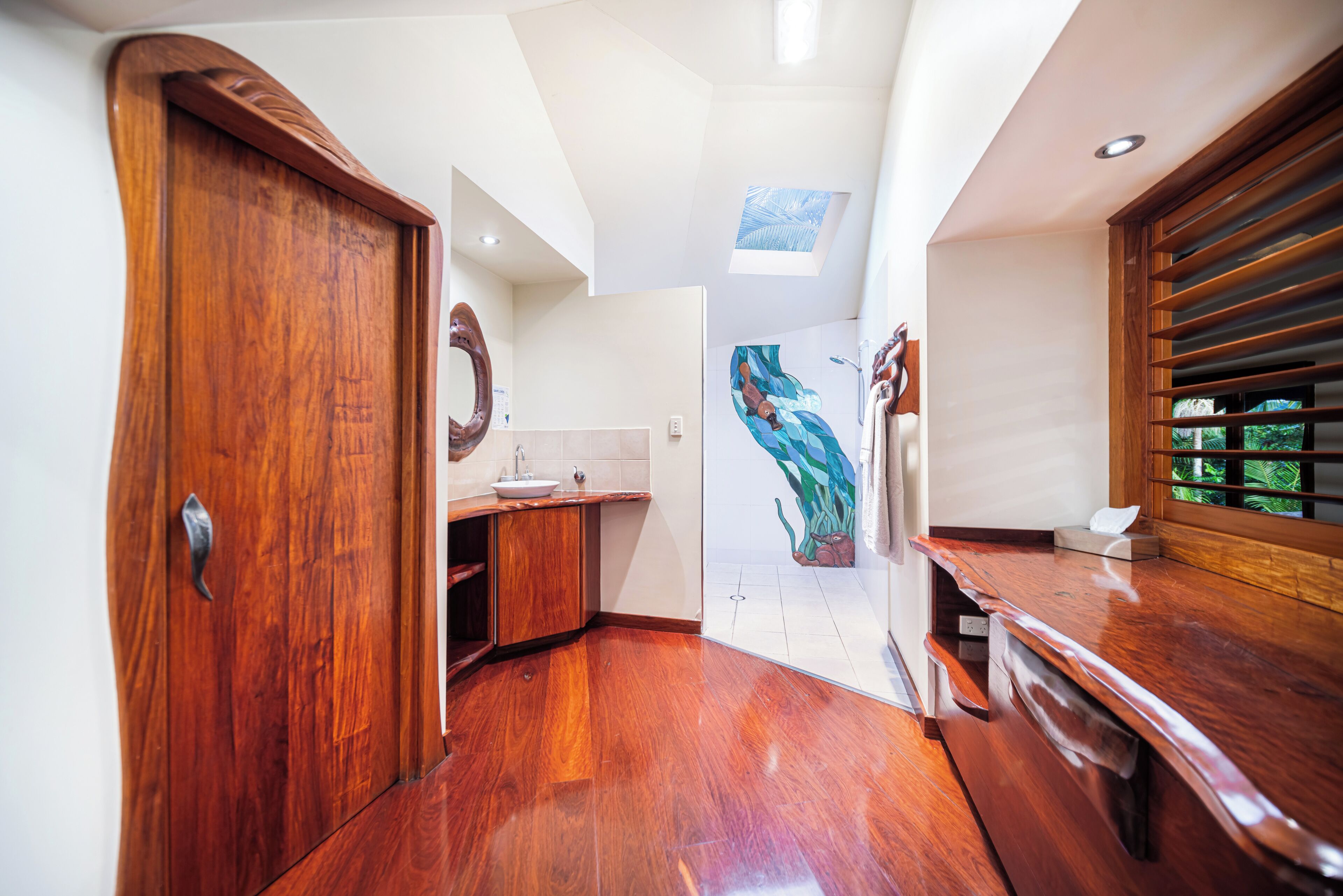 A modern kitchen with wooden cabinetry, a skylight, and a mural on the wall.