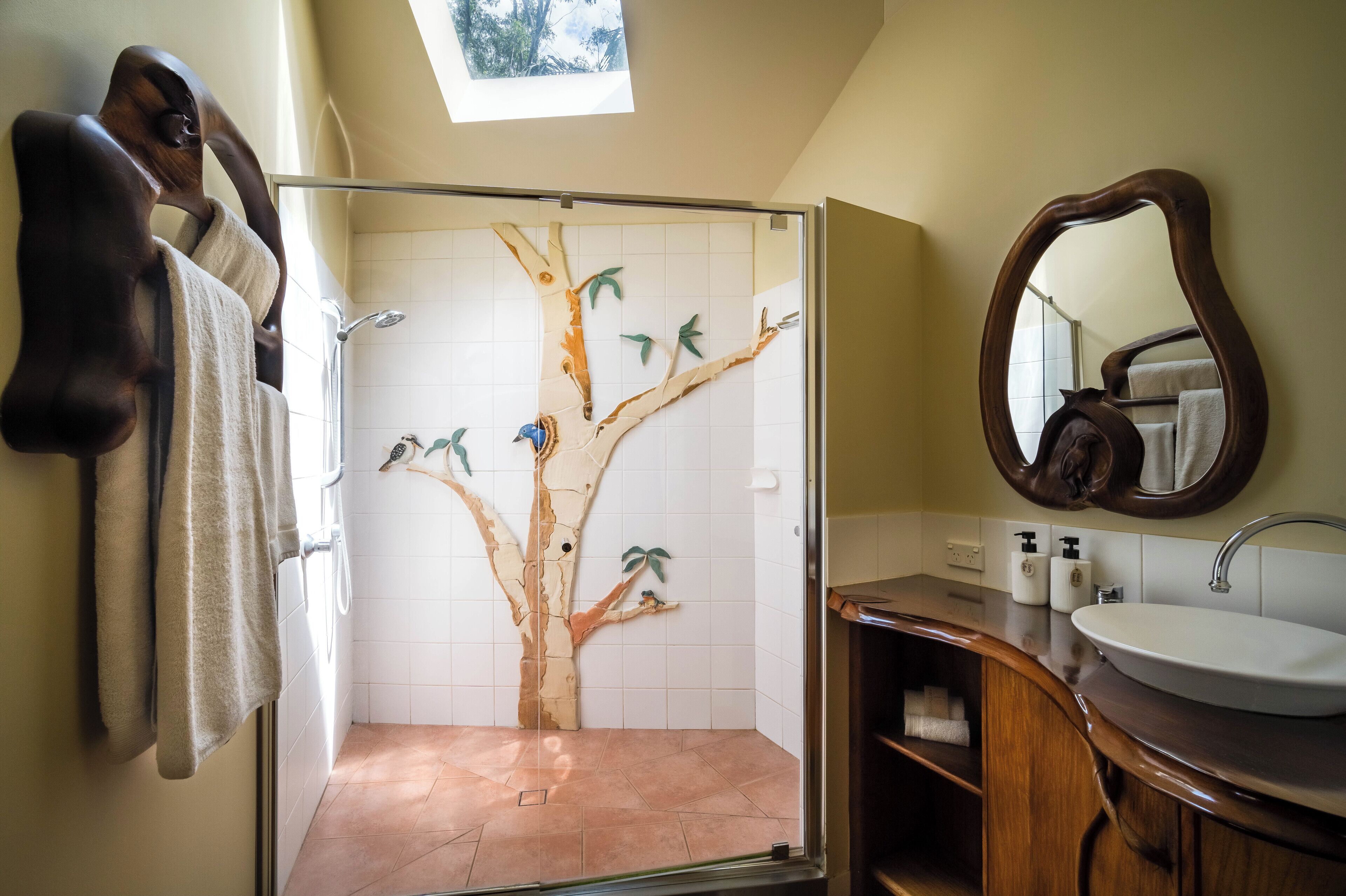 Un baño con ducha, lavamanos, espejo y toallero.