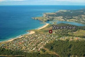 An aerial view of a coastal town with a marked location. - Beachfront Apartments Narooma (North Narooma)