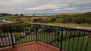 A balcony with a view of the ocean and a grassy landscape. - Beachfront Apartments Narooma (North Narooma)