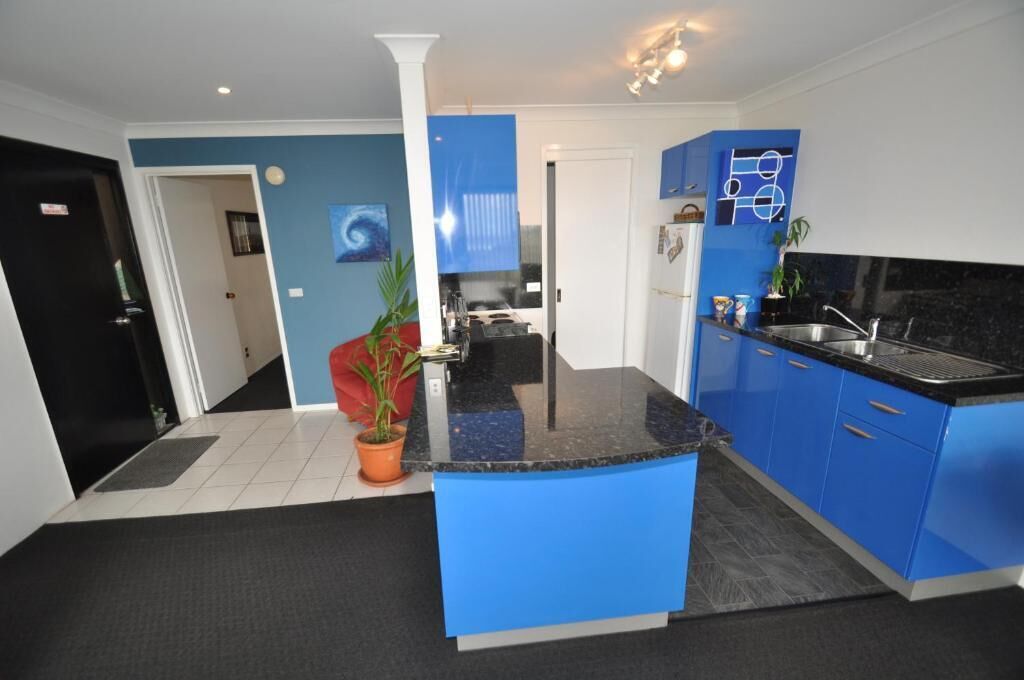 A modern kitchen with blue cabinets, a black countertop, and a central island.