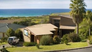 A coastal property with a house, a parked vehicle, and a view of the ocean. - Beachfront Apartments Narooma (North Narooma)