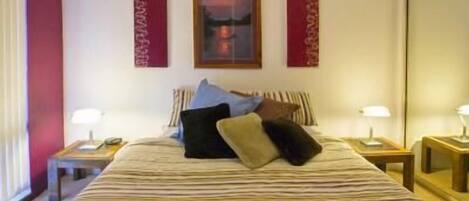 A hotel room with a large bed, two bedside tables, and a nightstand.