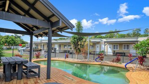 A pool area with lounge chairs and a covered seating area. - Ned Kelly's Motel (Tinana)